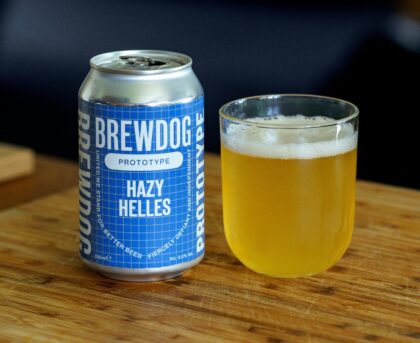 Close-up of BrewDog Hazy Helles prototype beer in a can and glass on a wooden surface.
